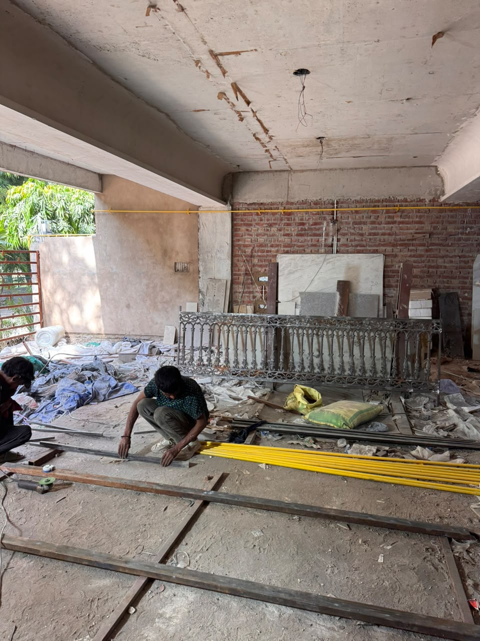 Fabricators assembling steel gate and railing sections in the stilt level of our Sector 41F Noida kothi