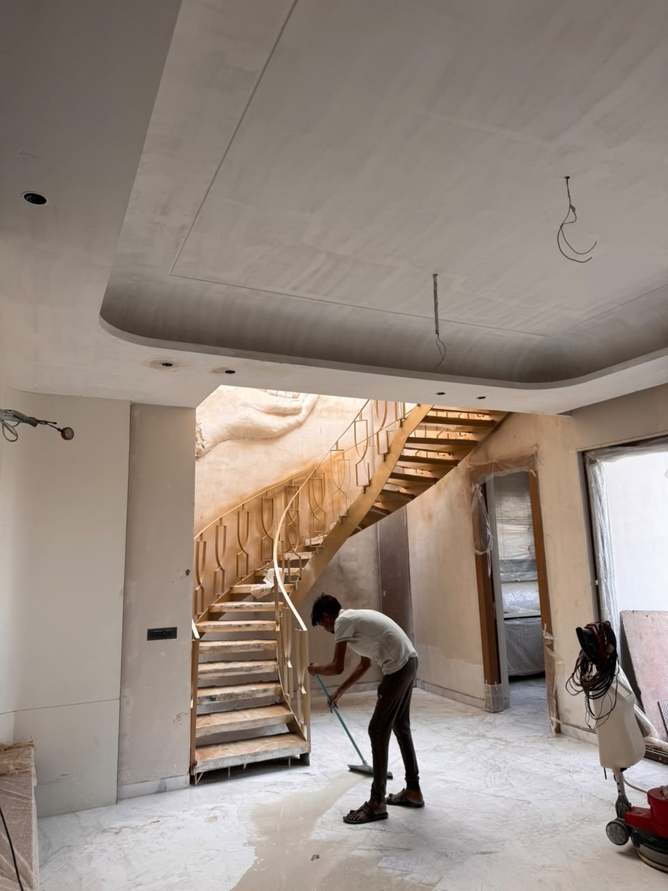 Marble floor polishing beneath a curved staircase and cove-lit false ceiling at our Sector 41F Noida kothi